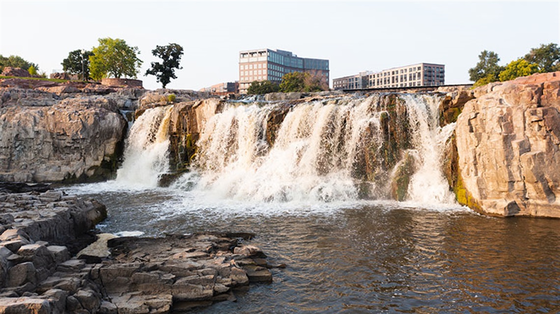 Waterfalls at Falls Park in Sioux Falls, South Dakota with downtown buildings behind