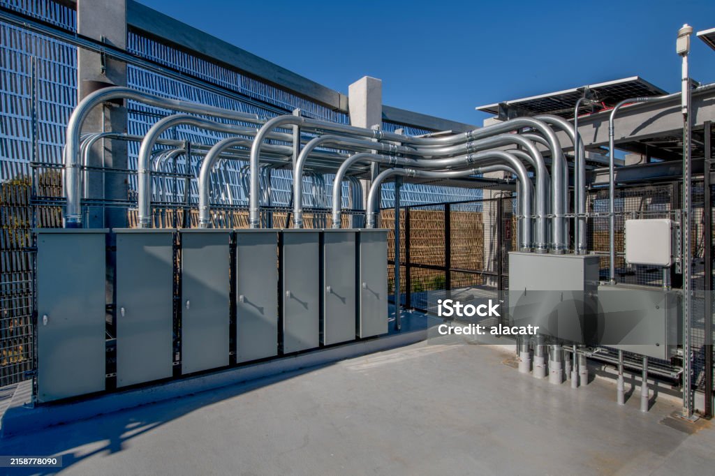 Commercial electrical panels and overhead metal conduit on a rooftop equipment platform