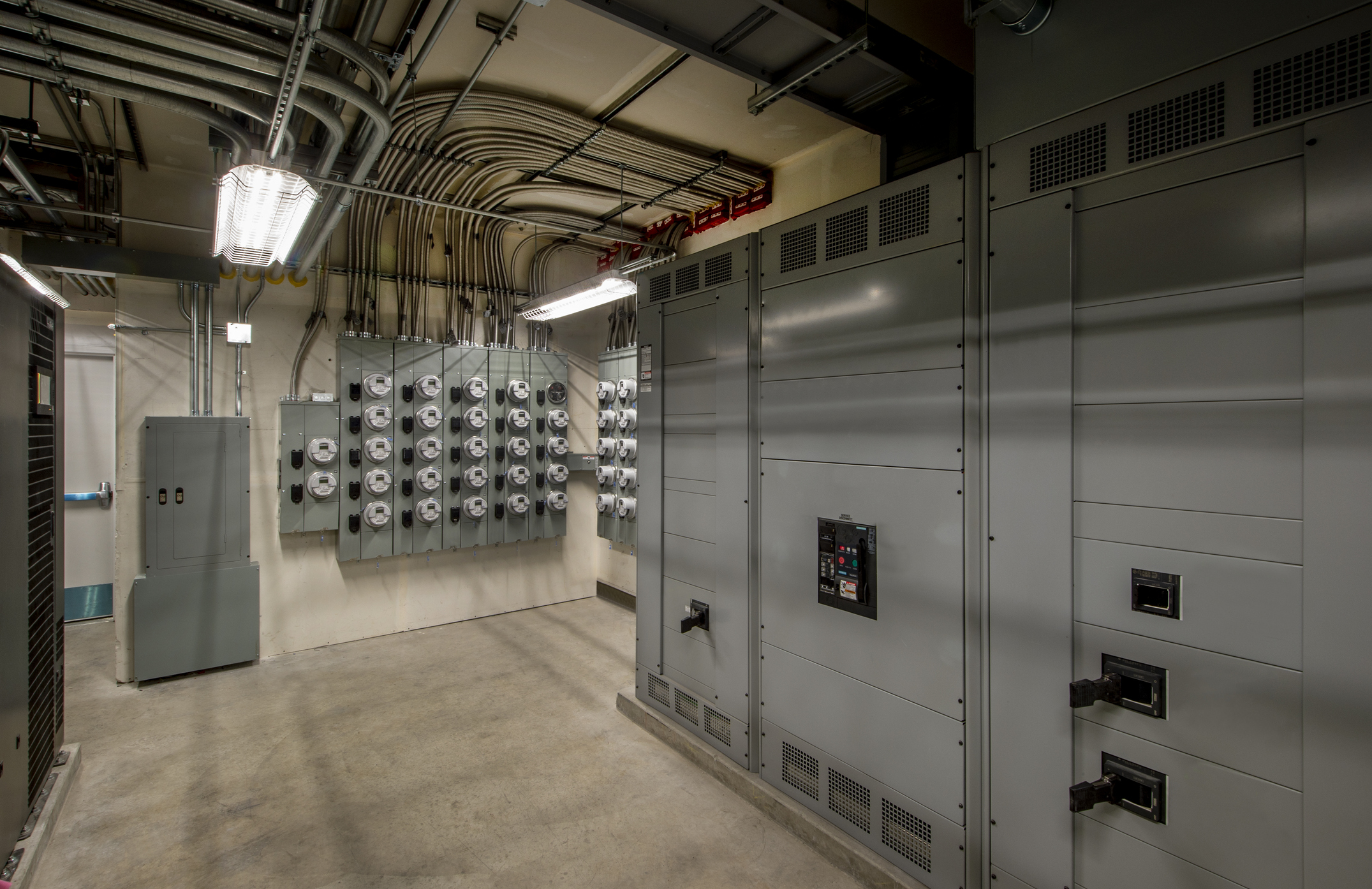 Commercial electrical switchgear and metering panels with overhead conduit in a service room