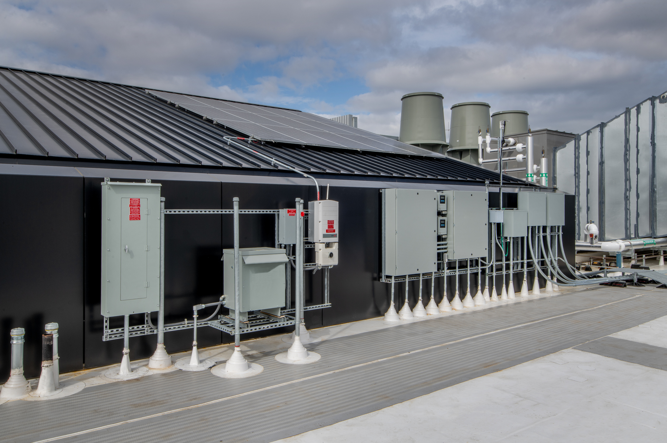 Rooftop solar panels with electrical disconnects, conduit, and panels on a commercial building